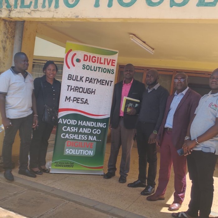 The Digilive Solutions team at the launch event outside Kilimo House, the Bungoma Ministry of Agriculture office, beside a Digilive banner